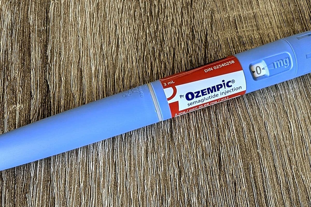Caneta injetável azul de semaglutida, com rótulo vermelho e branco, sobre uma mesa de madeira