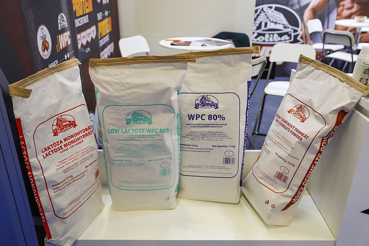 Quatro sacos de papel com lactose, concentrado de proteína do soro de leite WPC 80% e permeado de soro sobre um balcão de estande
